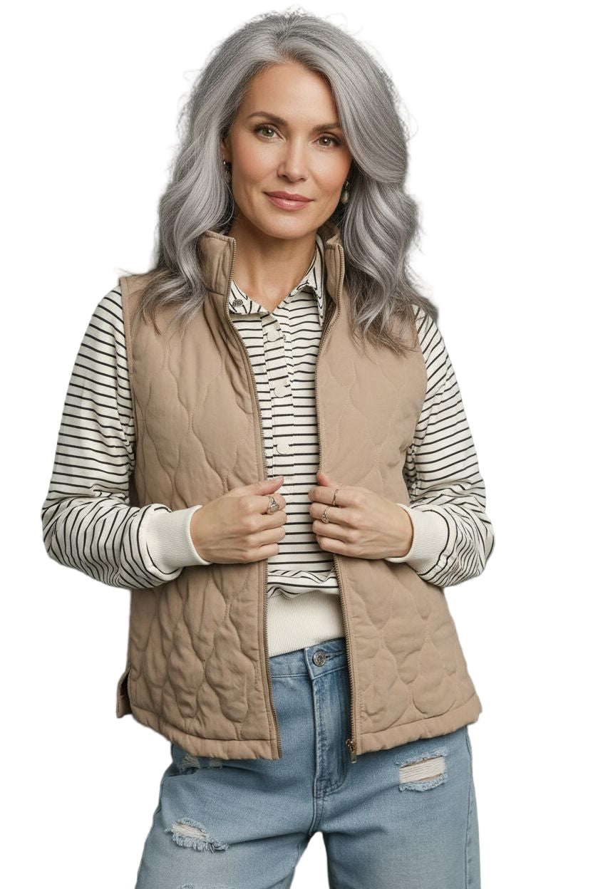 Woman wearing a beige quilted vest over a striped shirt with a gray background
