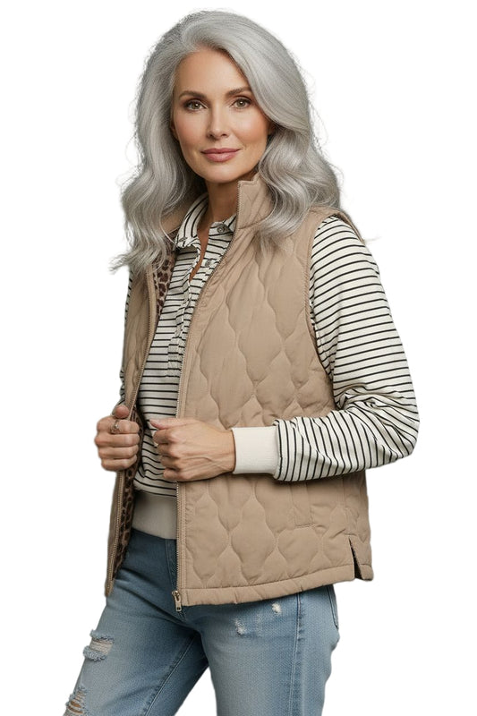 Woman wearing a beige quilted vest over a striped shirt with a gray background